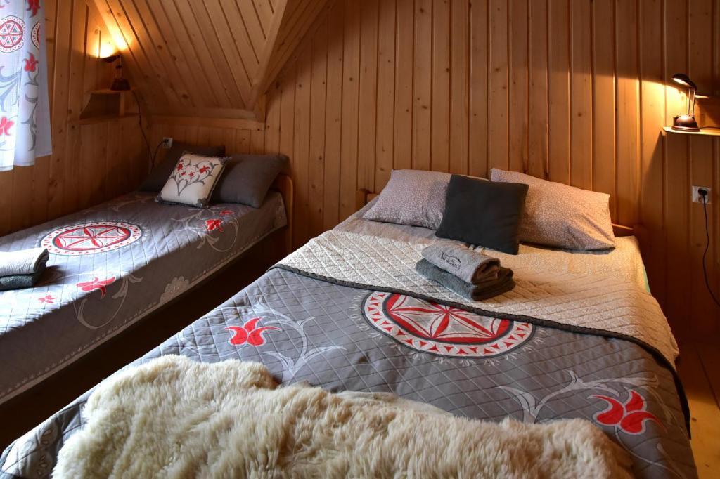 two beds in a room with wooden walls at Na ubocy in Brzegi