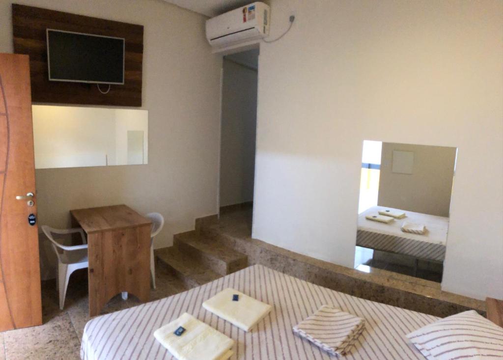 Cette chambre comprend un lit, une table et un miroir. dans l'établissement Hotel Butantã, à São Paulo