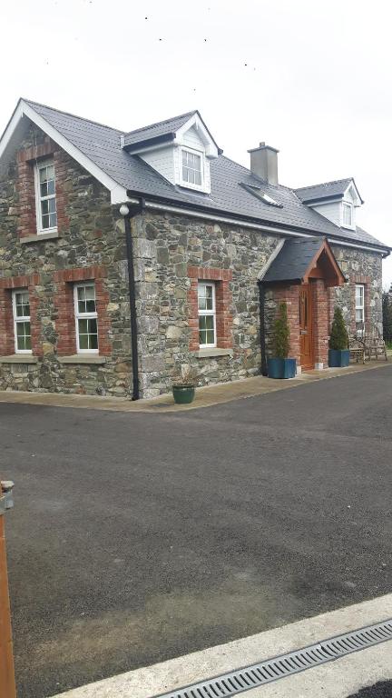 un bâtiment en pierre avec une rue aphalt en face dans l'établissement Nellies Cottage B&B, à Kilcogy