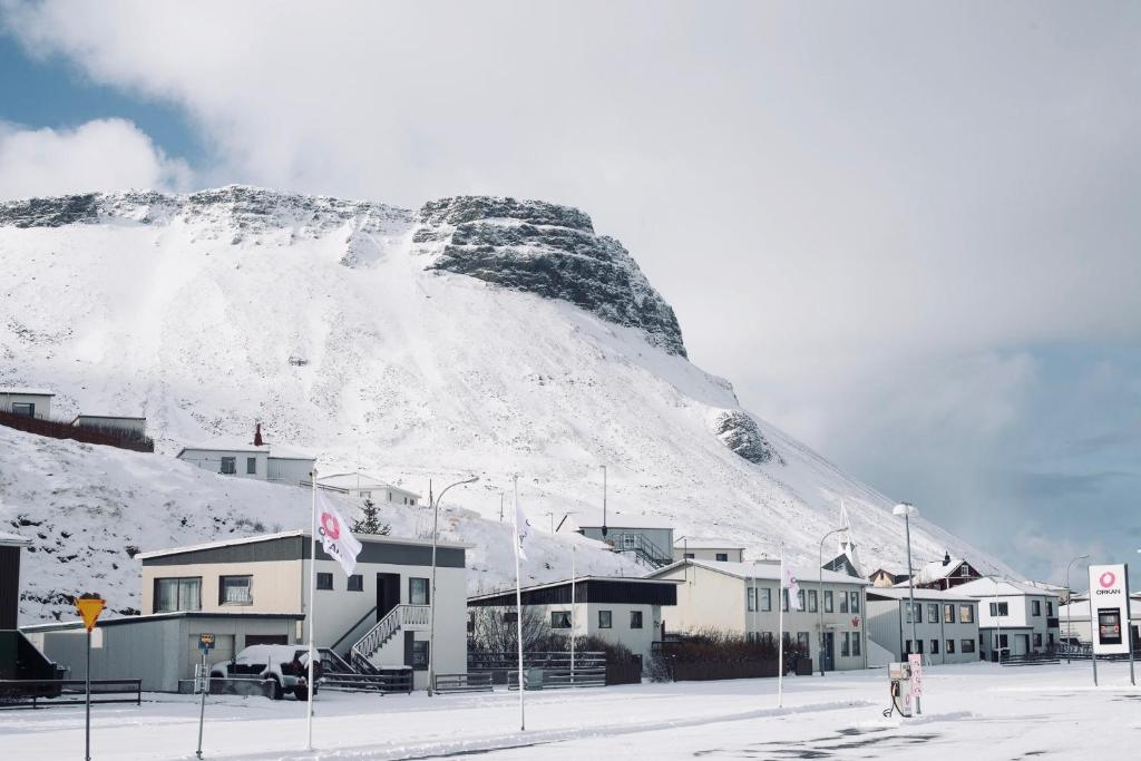 a snow covered mountain behind a town with houses at Experience Beautiful Iceland in Ólafsvík
