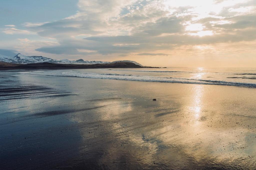 a beach with the ocean and mountains in the background at Experience Beautiful Iceland in Ólafsvík