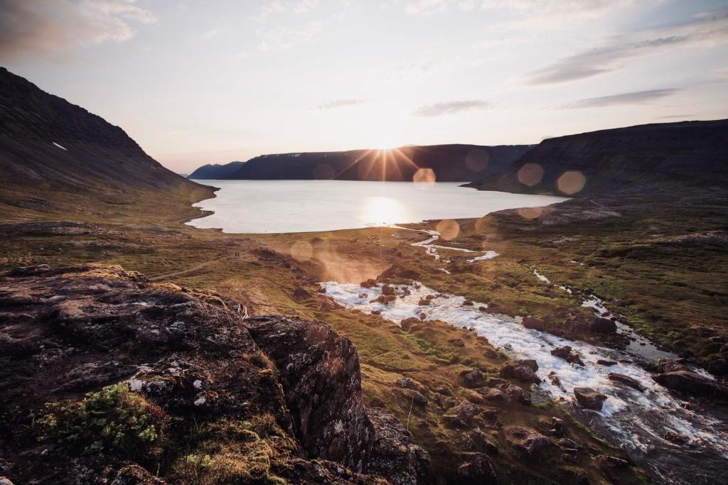 a sunset over a beach with the ocean and rocks at Experience Beautiful Iceland in Ólafsvík