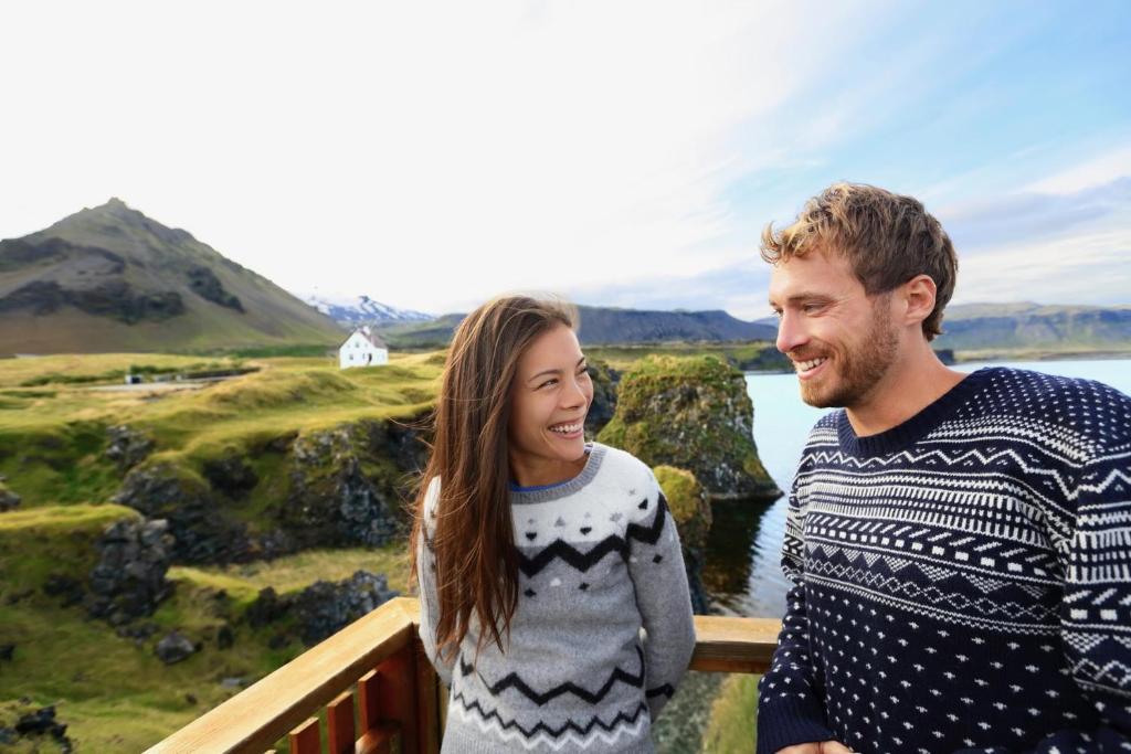 a man and a woman standing on a bridge near the water at Experience Beautiful Iceland in Ólafsvík