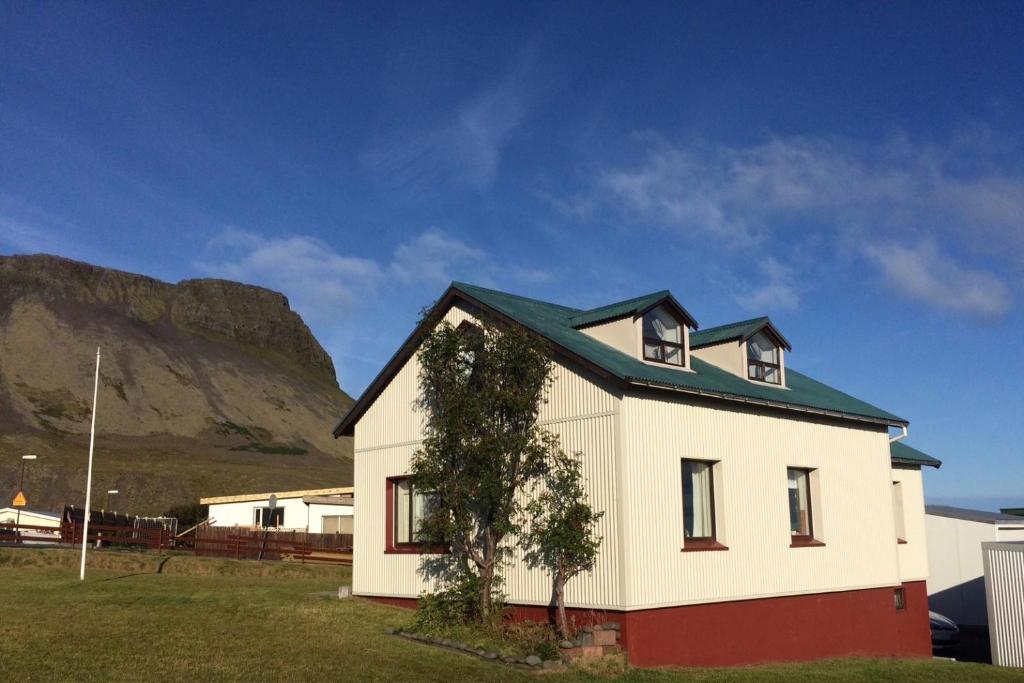 a white house with a mountain in the background at Experience Beautiful Iceland in Ólafsvík