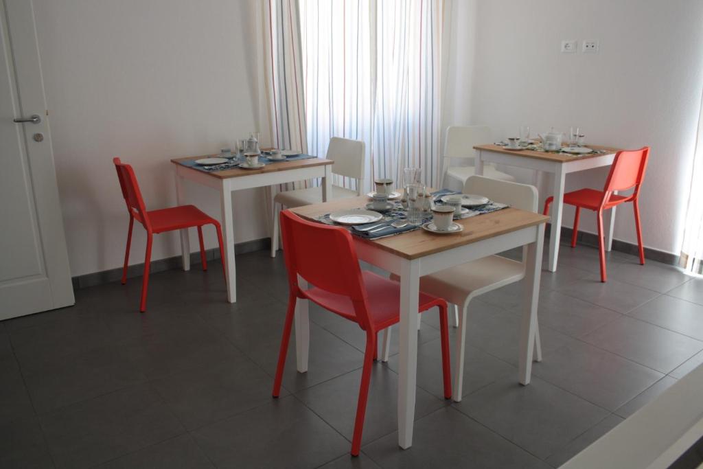 une salle à manger avec quatre tables et des chaises rouges dans l'établissement Gli olivi, à Oliena