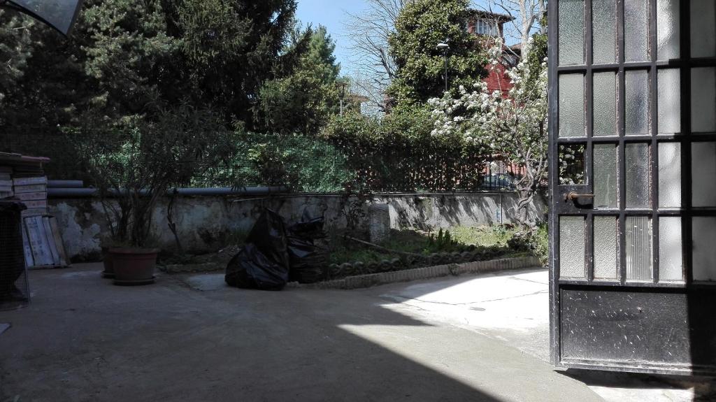 an open door to a yard with a stone fence at Residenza villoresi in Cormano