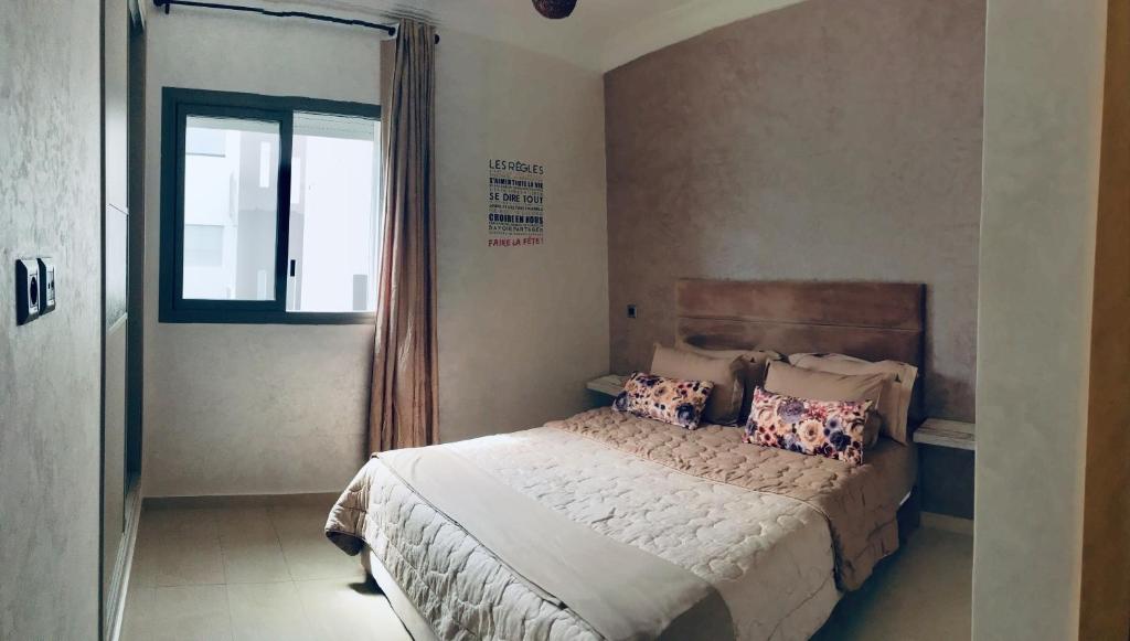 een slaapkamer met een bed met kussens en een raam bij Holiday Home Blanca Beach in Sidi Rahal