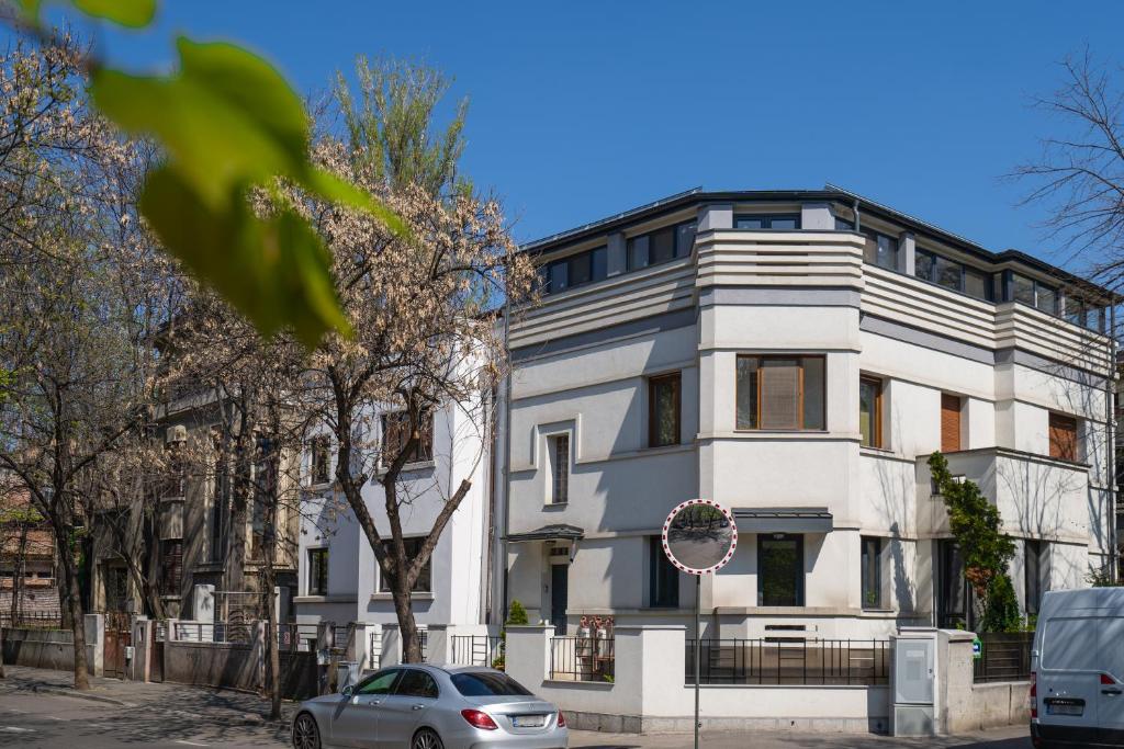 ein weißes Haus mit einem davor geparkt in der Unterkunft W29 - Cozy Deluxe Studio in Bukarest
