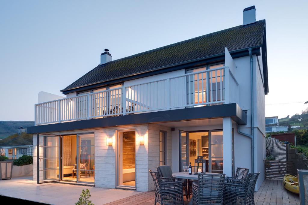 a house with a balcony and a table on a deck at Beam Ends in Beesands