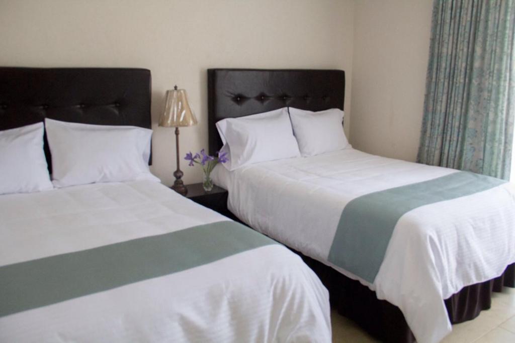 2 letti posti uno accanto all'altro in una camera da letto di Hotel Nube Nueve a Chignahuapan