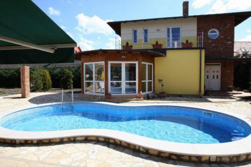 a large swimming pool in front of a house at Gasthaus Joó-Wellness Pension in Rábapaty