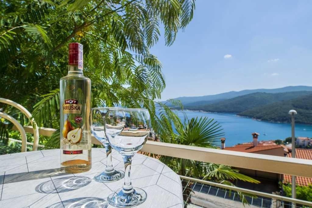 una bottiglia di vino seduta su un tavolo con un bicchiere di Apartments Gracia - with great view a Rabac