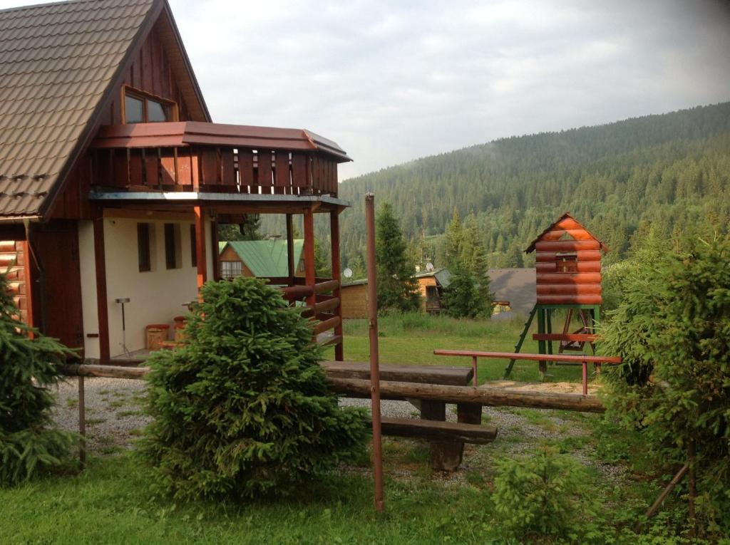 un chalet avec une aire de jeux à côté d'une maison dans l'établissement Chata Janka, à Oravice