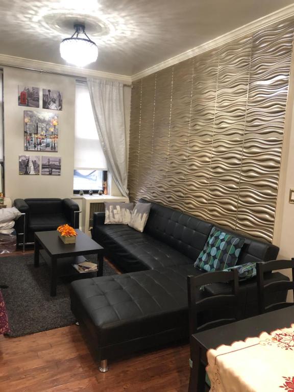 sala de estar con sofá de cuero negro en Modern 2 Bedroom Apartment NYC, en Nueva York