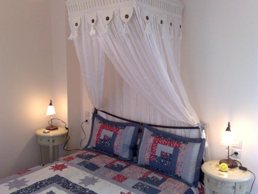 Dreamcatcher-Luxury Maisonette No.1 في كالافريتا: غرفة نوم مع سرير مع مظلة وجلستين ليلية