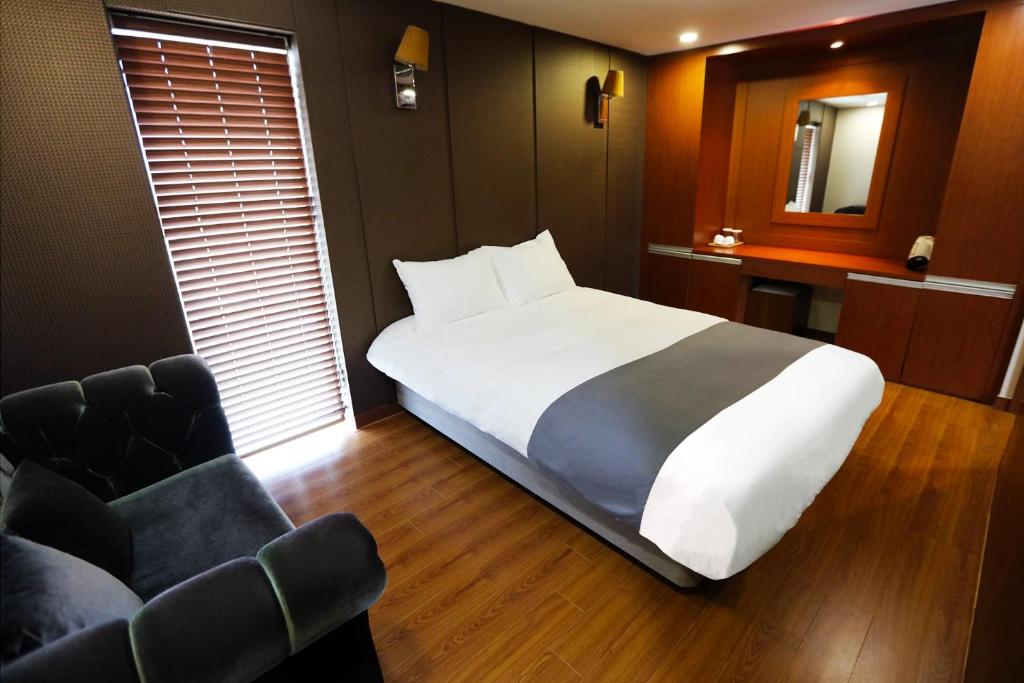 a bedroom with a large white bed and a chair at Sobaeksan Punggi Spa Resort in Yeongju