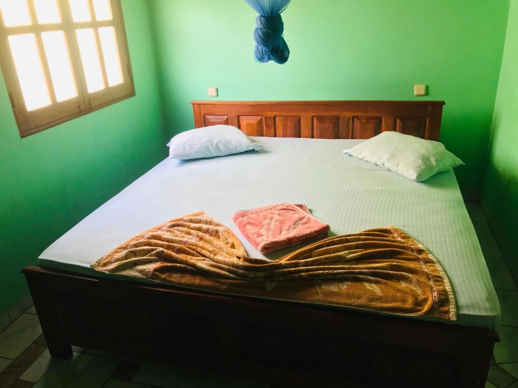 Una cama en una habitación verde con una manta. en Temple Flower Guest, en Kirinda