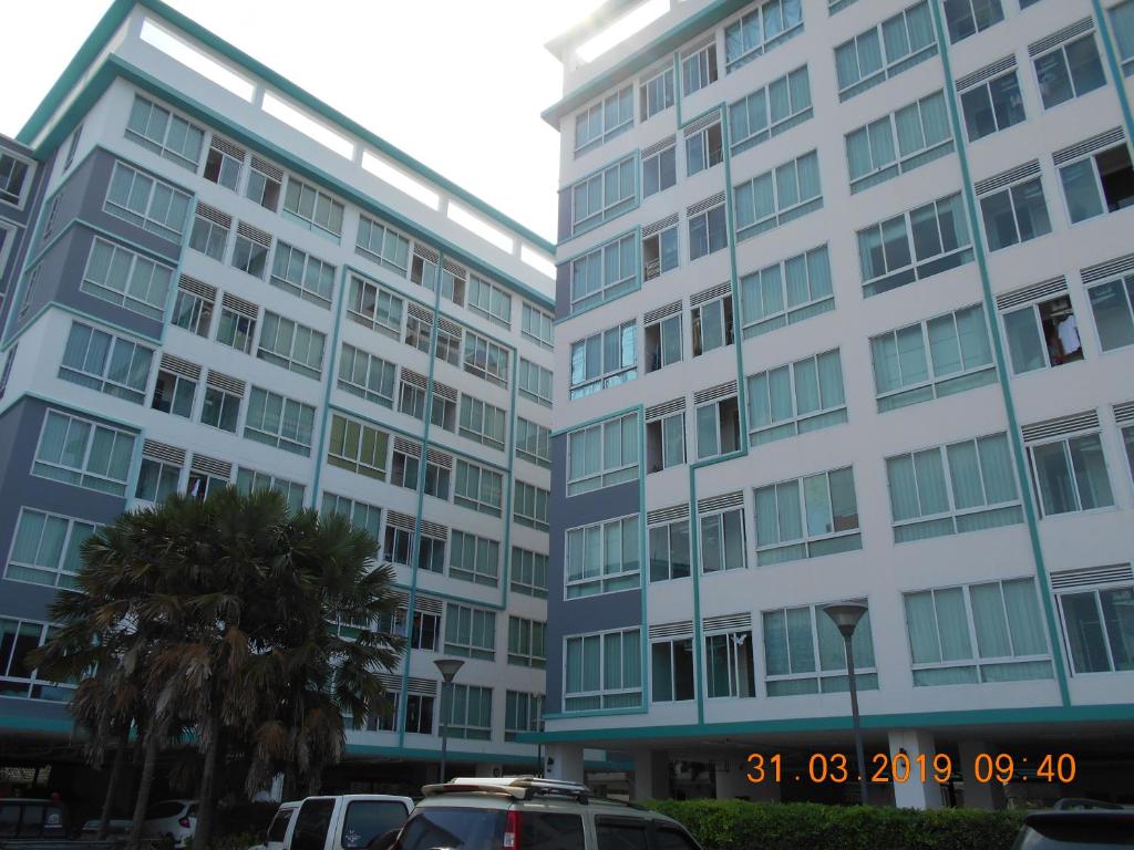 ein großes weißes Gebäude mit davor geparkt in der Unterkunft The Hug Condo Bangsaen in Bangsaen