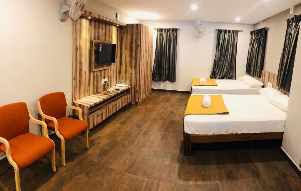 a hotel room with two beds and two chairs at Sharada Residency in Somvārpet