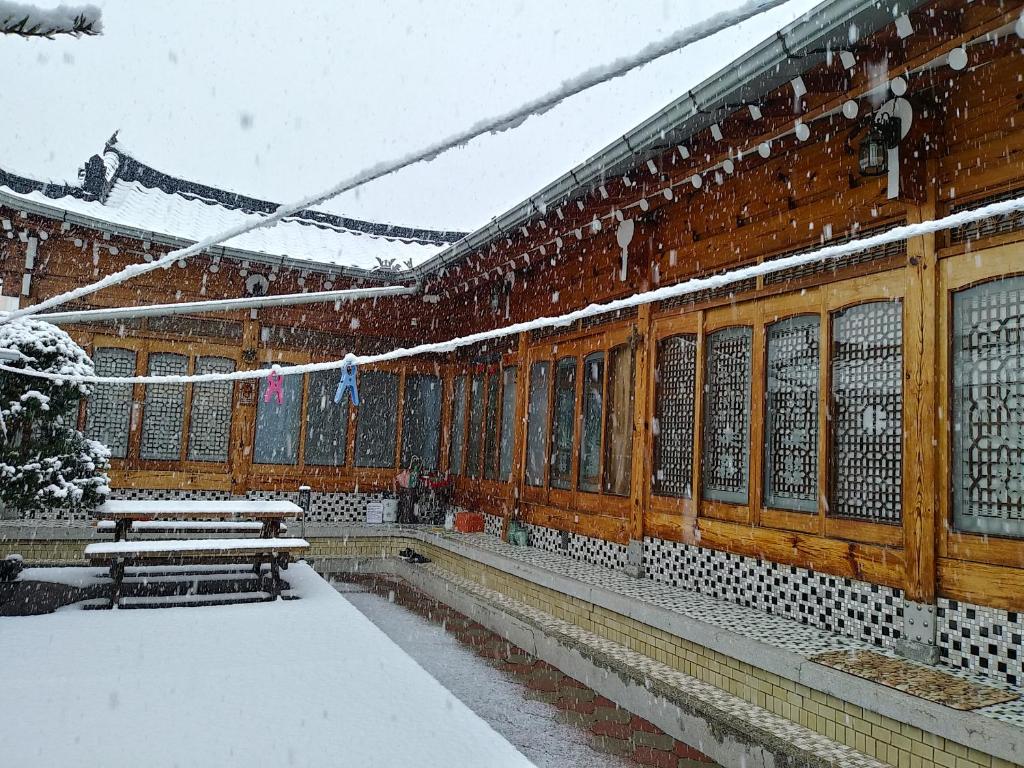 un edificio cubierto de nieve con bancos y ventanas en Wolyeongchae, en Andong
