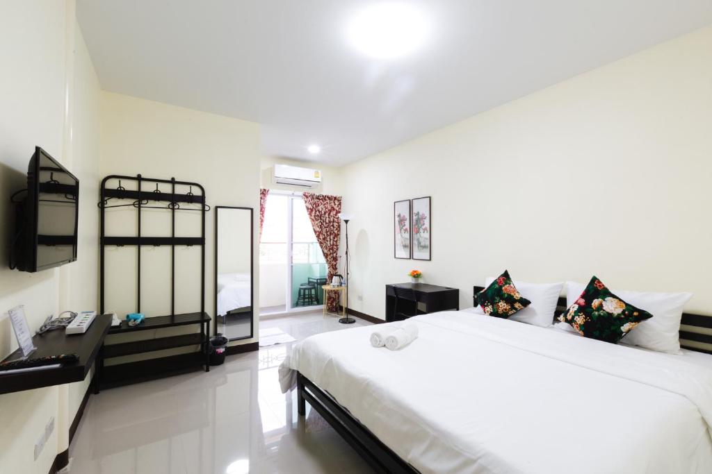A bright double bedroom with a wall-mounted TV, open storage, and balcony access.