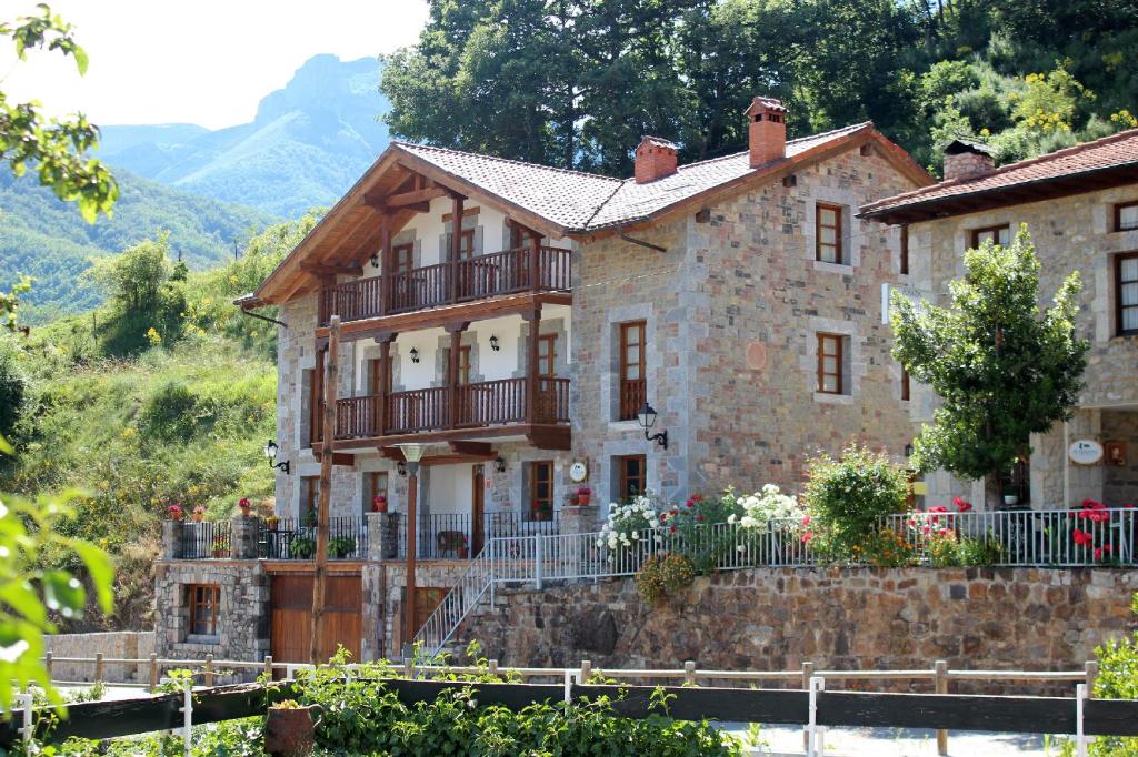 une grande maison en pierre sur une colline avec des montagnes en arrière-plan dans l'établissement Posada Sobrevilla, à Espinama