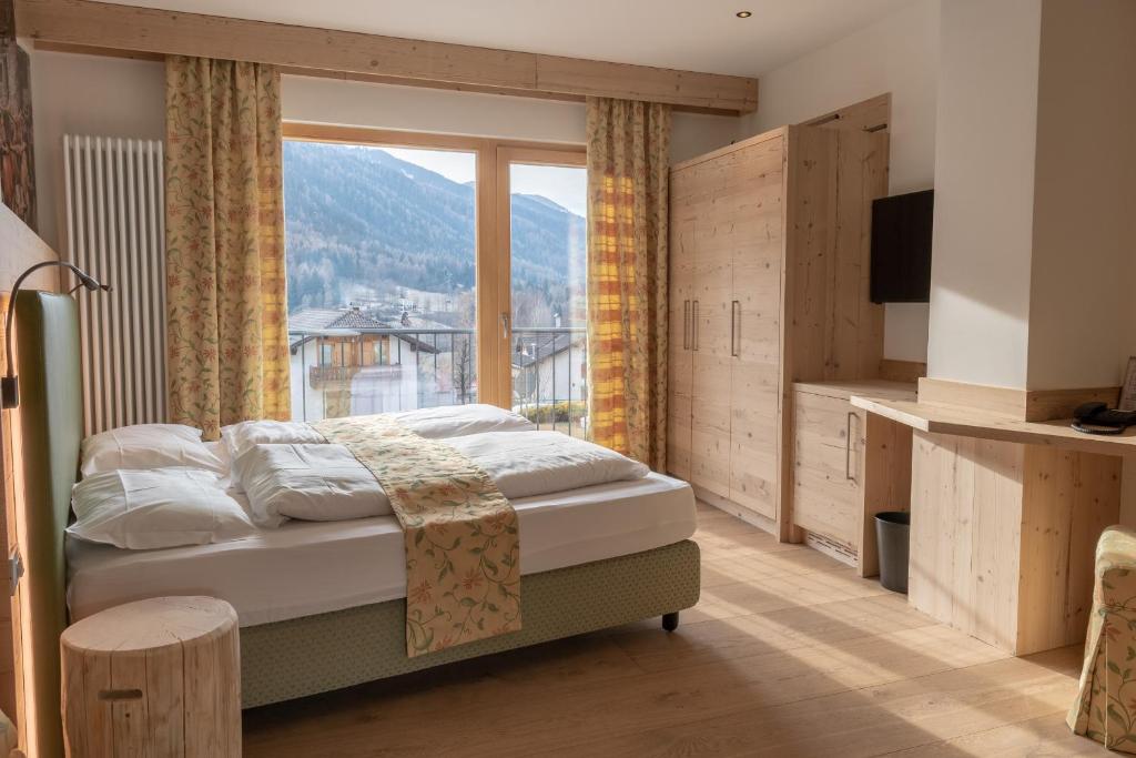 a bedroom with a bed and a large window at Hotel Eccher 3 stelle Superior in Mezzana