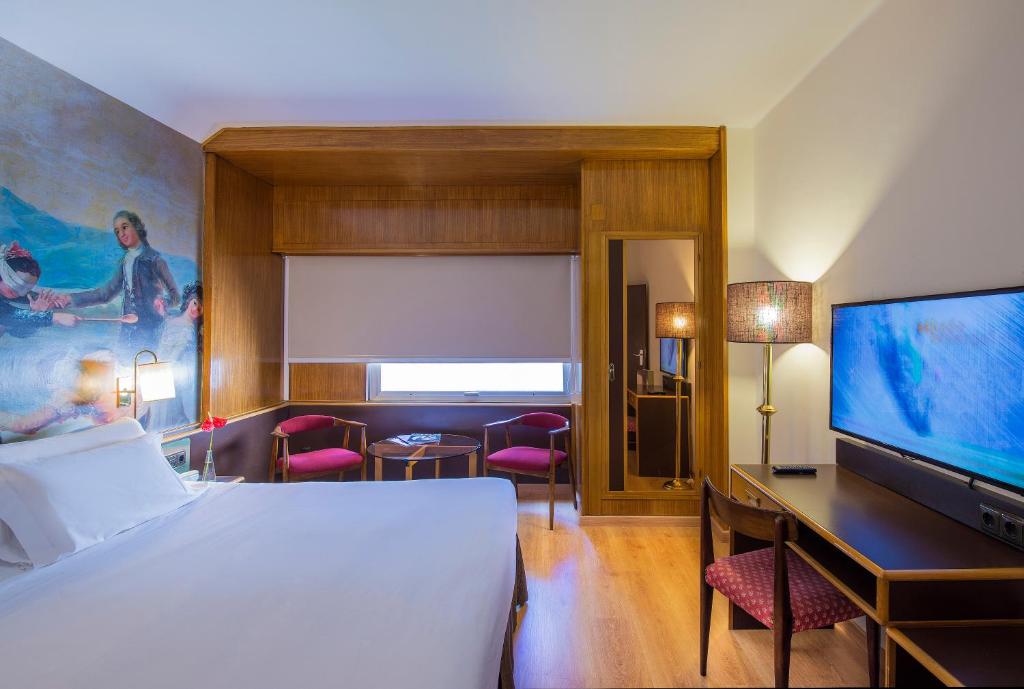a hotel room with a bed and a flat screen tv at Hotel Goya in Zaragoza