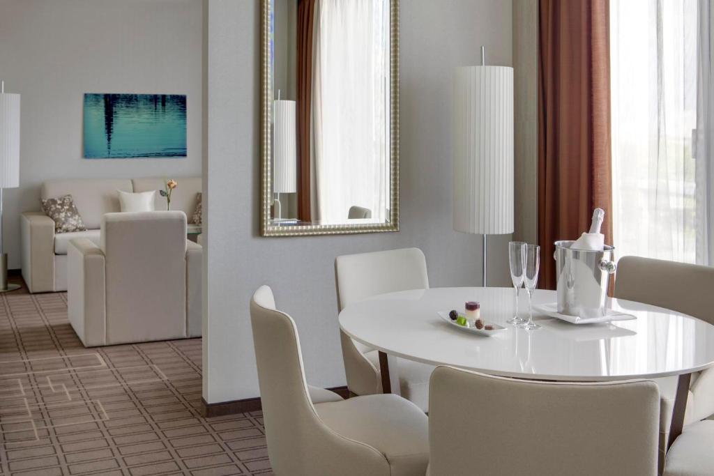 a white dining room with a white table and chairs at Steigenberger Hotel Bremen in Bremen