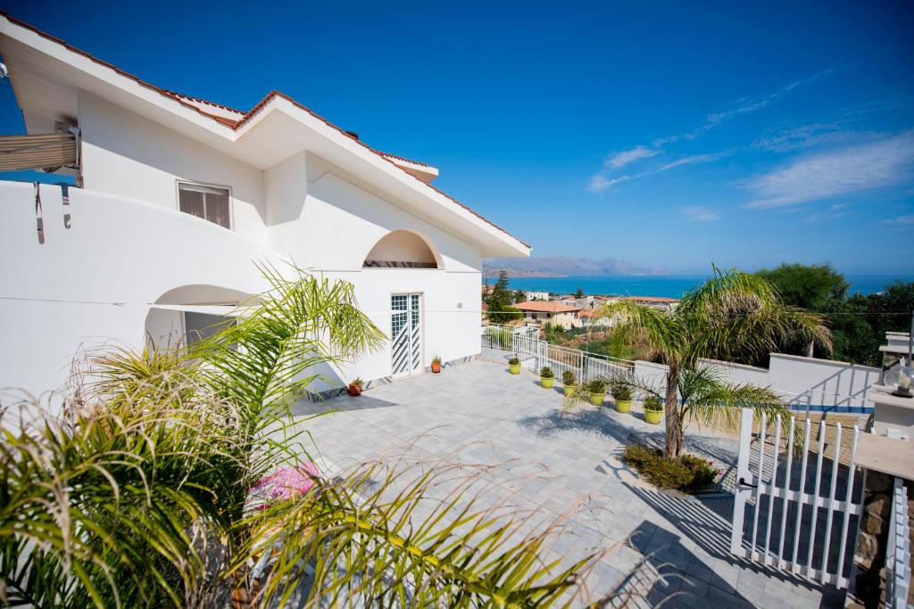 una casa bianca con balcone con vista sull'oceano sullo sfondo di Villa Trinacria Apartments ad Alcamo Marina
