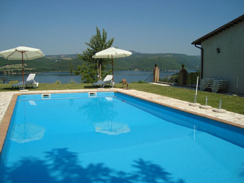 einen großen blauen Pool mit Blick auf das Wasser in der Unterkunft Poggio San Giacomo in Baschi