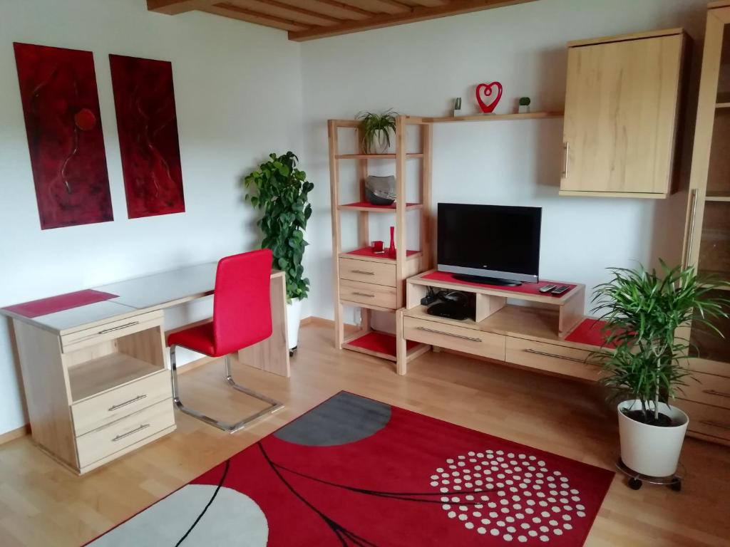 a living room with a desk and a red chair at Ferienwohnung Helmberger in Burgkirchen in Burgkirchen an der Alz