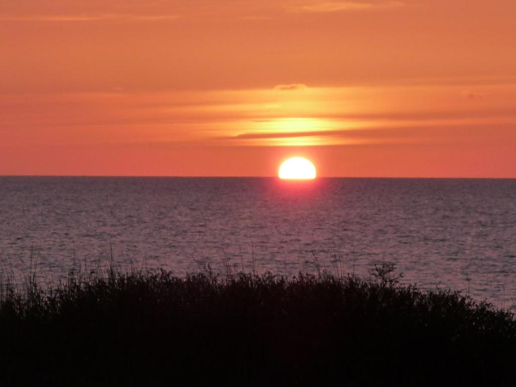 una puesta de sol sobre el océano con la puesta de sol en Haus Nordseebrise, en Cuxhaven