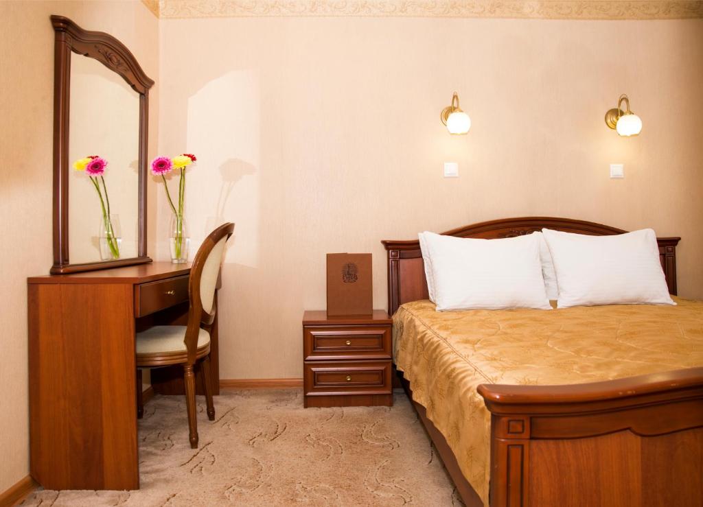 - une chambre avec un lit, un bureau et un miroir dans l'établissement Hotel Rus, à Irkoutsk