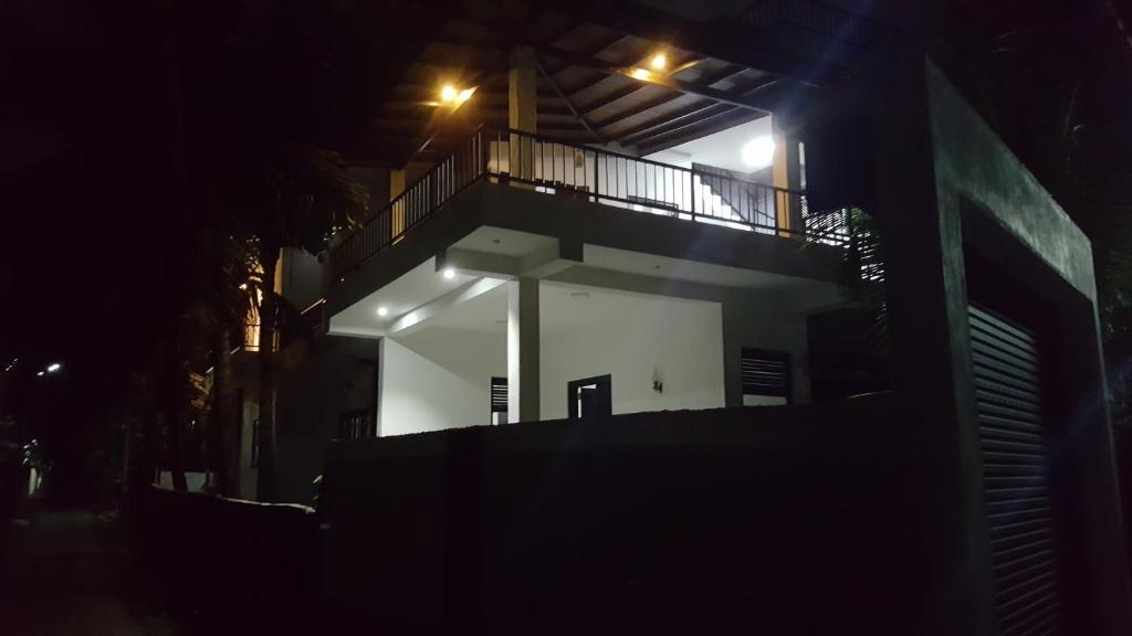 een wit gebouw met een balkon in de nacht bij COCO house in Galle