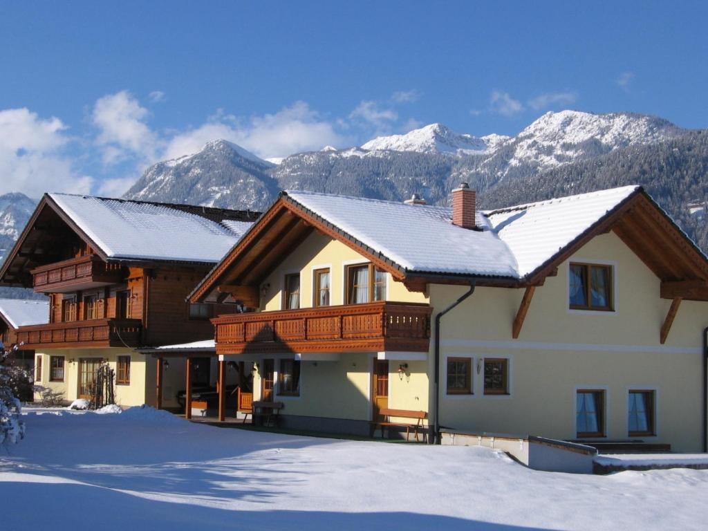 a house in the snow with mountains in the background at Land- und Appartementhaus Pircher in Aich