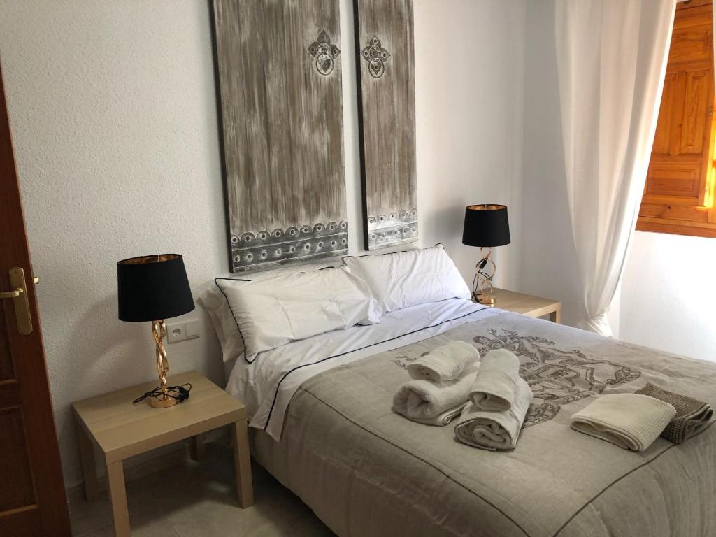 um quarto com uma cama com toalhas e 2 candeeiros em Apartamento SC Victoria em Cáceres