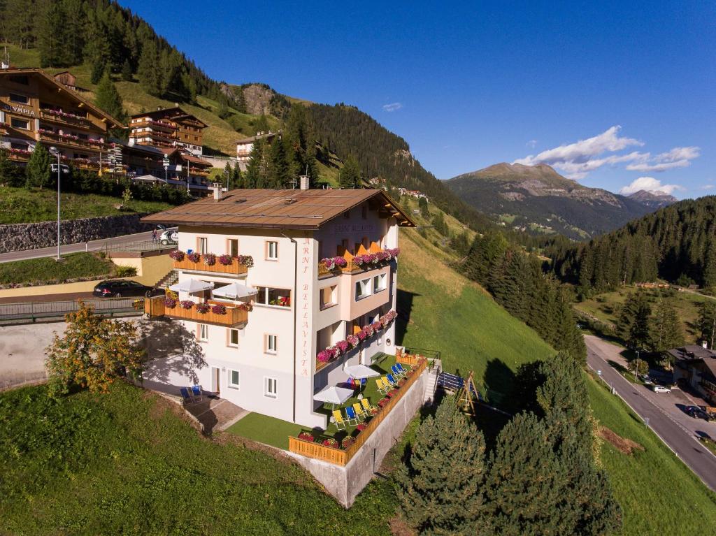 un grand bâtiment blanc sur une colline dans les montagnes dans l'établissement Garni Bellavista, à Arabba