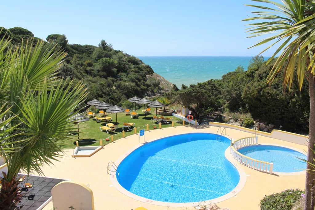 a swimming pool with the ocean in the background at Rocha Brava Village Resort in Carvoeiro