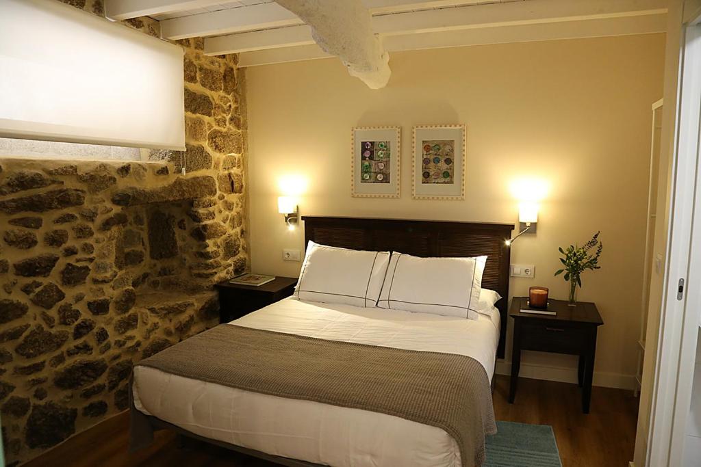 a bedroom with a bed and a stone wall at Casa Herreria in Caldas de Reis
