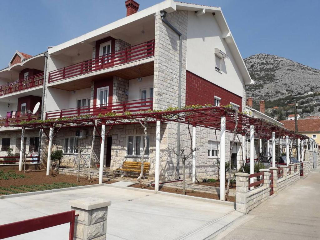 ein großes rot-weißes Gebäude mit einem Balkon in der Unterkunft Apartmani RADA in Trebinje