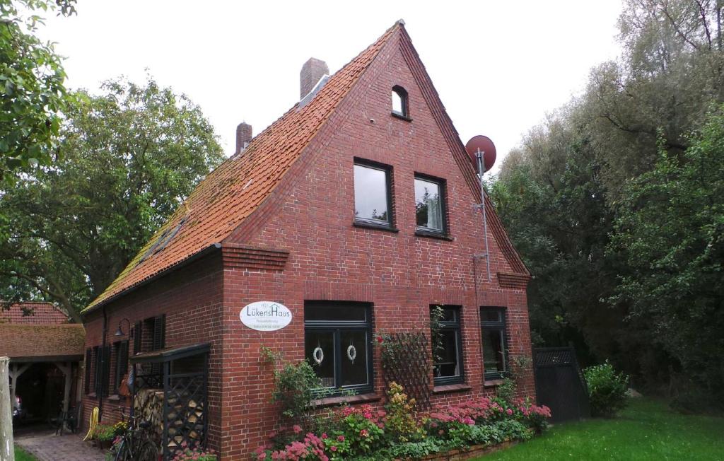 ein rotes Backsteinhaus mit zwei Fenstern und Blumen in der Unterkunft Ferienwohnung Lüken in Hooksiel