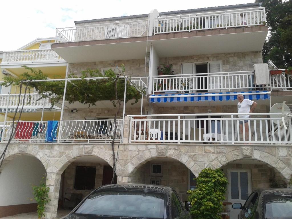 un hombre parado en el balcón de un edificio en Apartments Lončarević, en Slano