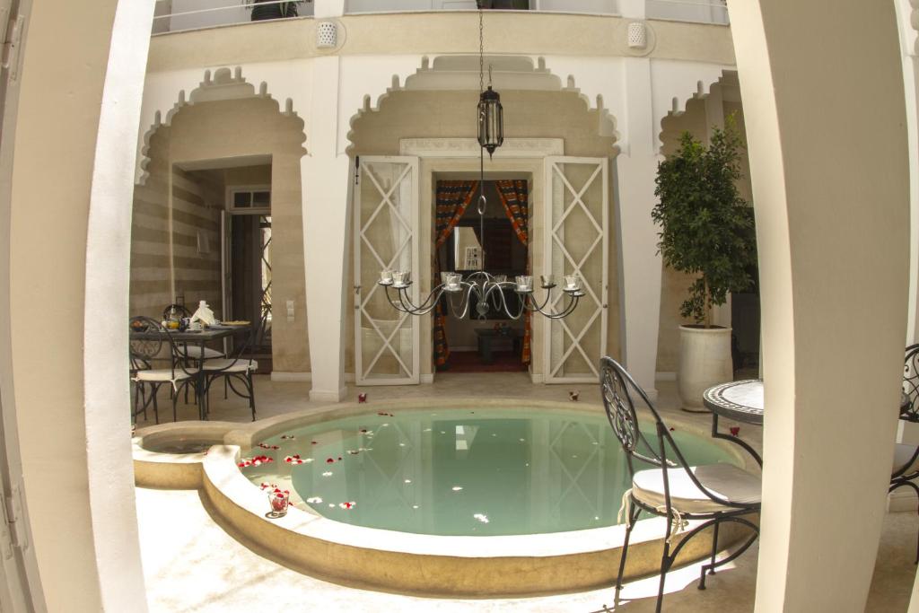 a pool in a building with chairs and a table at Riad THALGE in Marrakesh