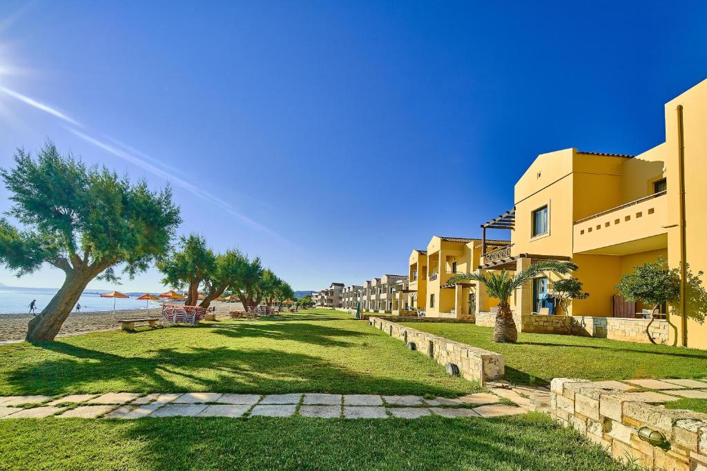 a row of buildings on a beach with trees and grass at Silver Beach Hotel & Apartments in Gerani Chanion