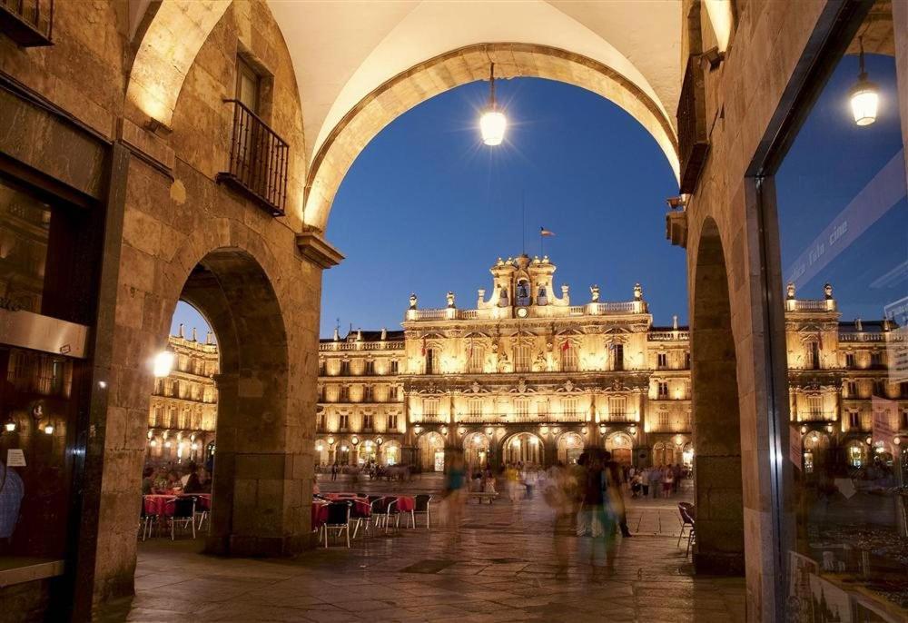 un gran edificio con gente caminando delante de él en Plaza de España, en Salamanca