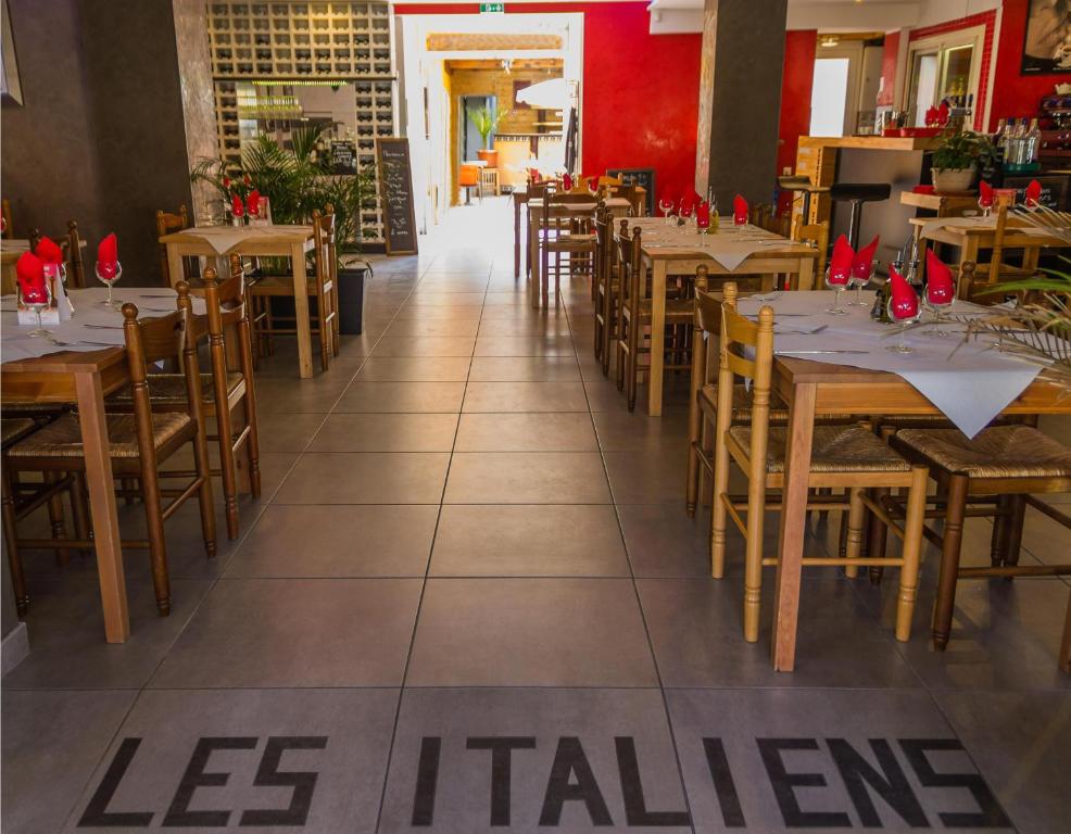 comedor con mesas y sillas de madera en Hôtel Les Italiens en Biscarrosse