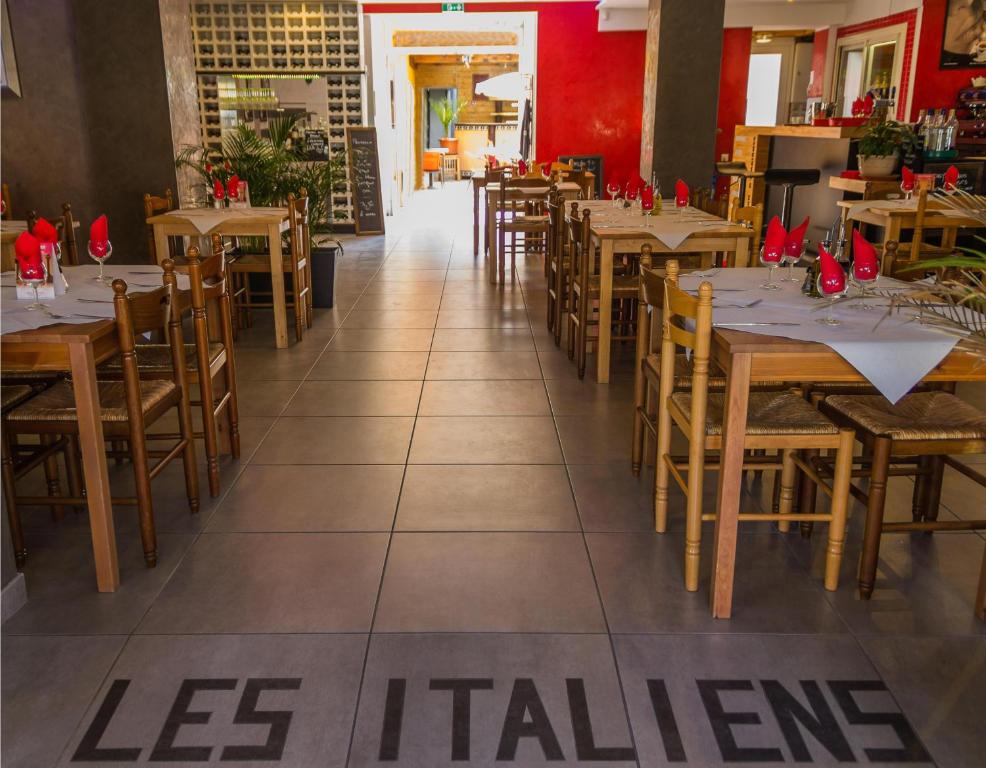 a dining room with wooden tables and chairs at Hôtel Les Italiens in Biscarrosse