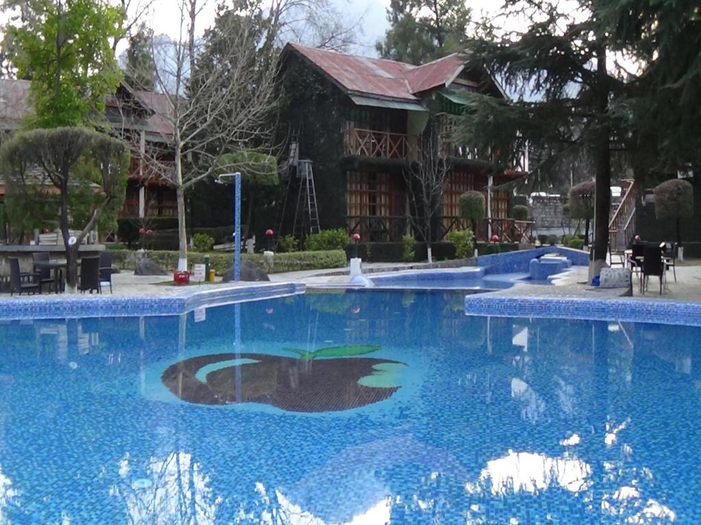 a swimming pool with blue water in front of a house at Apple Valley Resort in Kulu