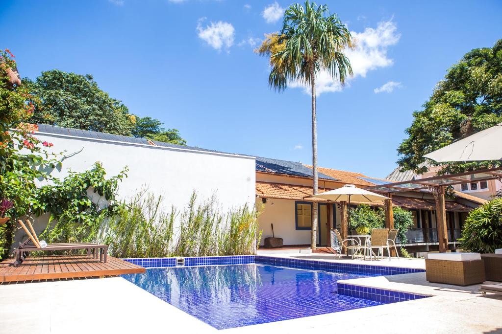 una piscina con una palmera y una casa en Pousada Villa Magnolia, en São João del Rei